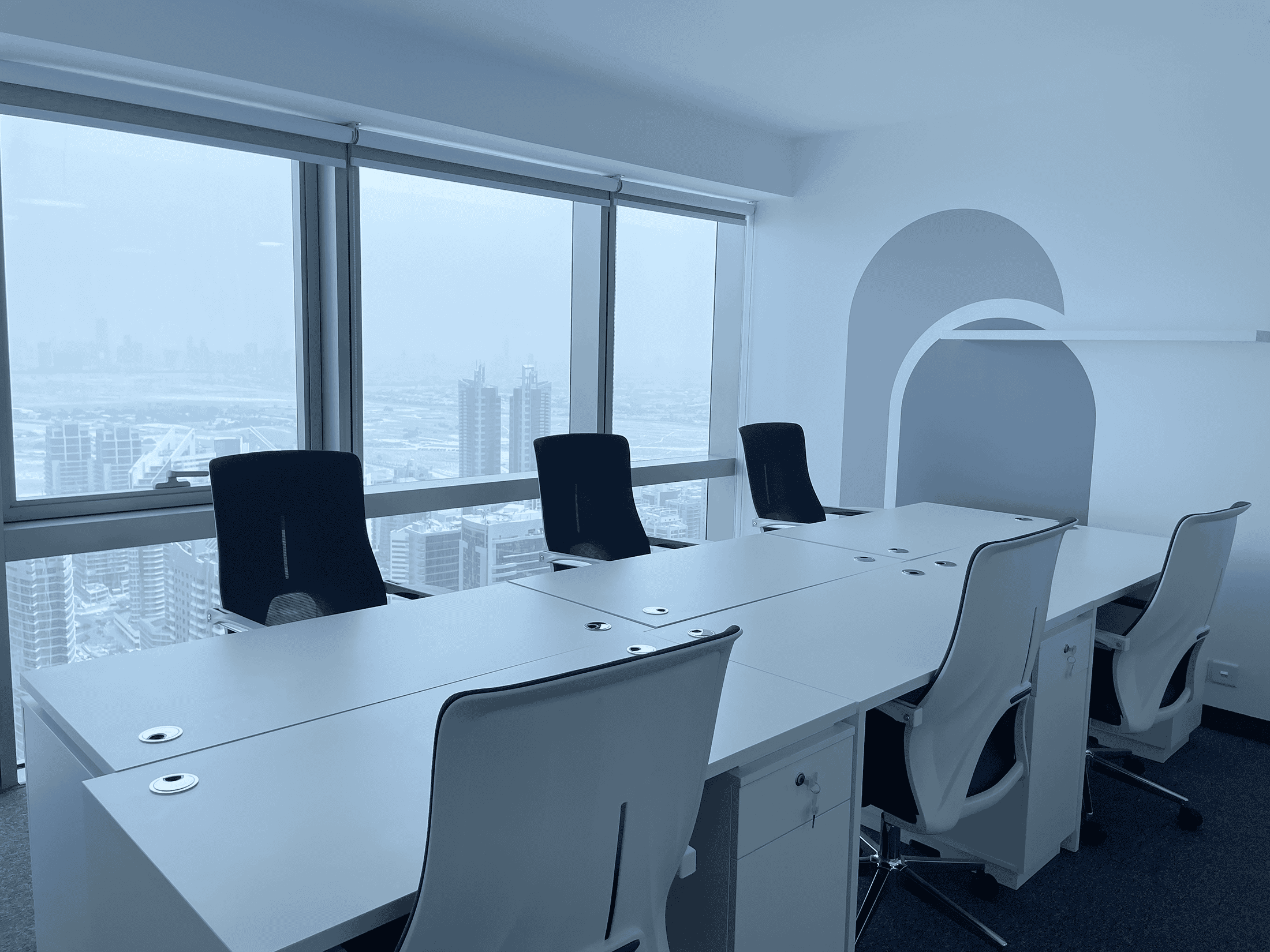 Bright office room with large windows overlooking Dubai's skyline, equipped with ergonomic chairs for productivity.