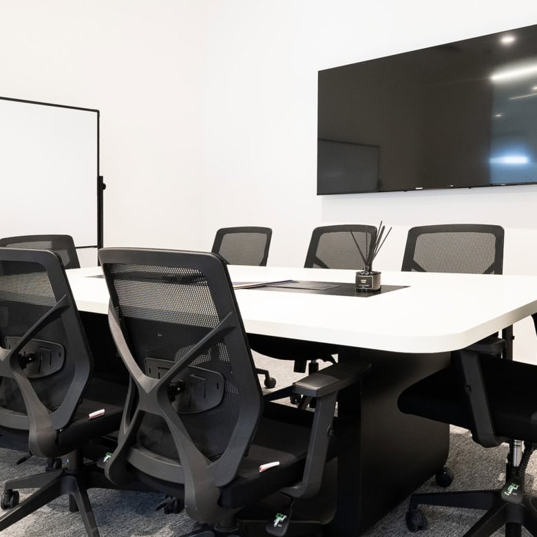 Spacious office conference room with ergonomic chairs, large screen and whiteboard for meetings and collaborative work.