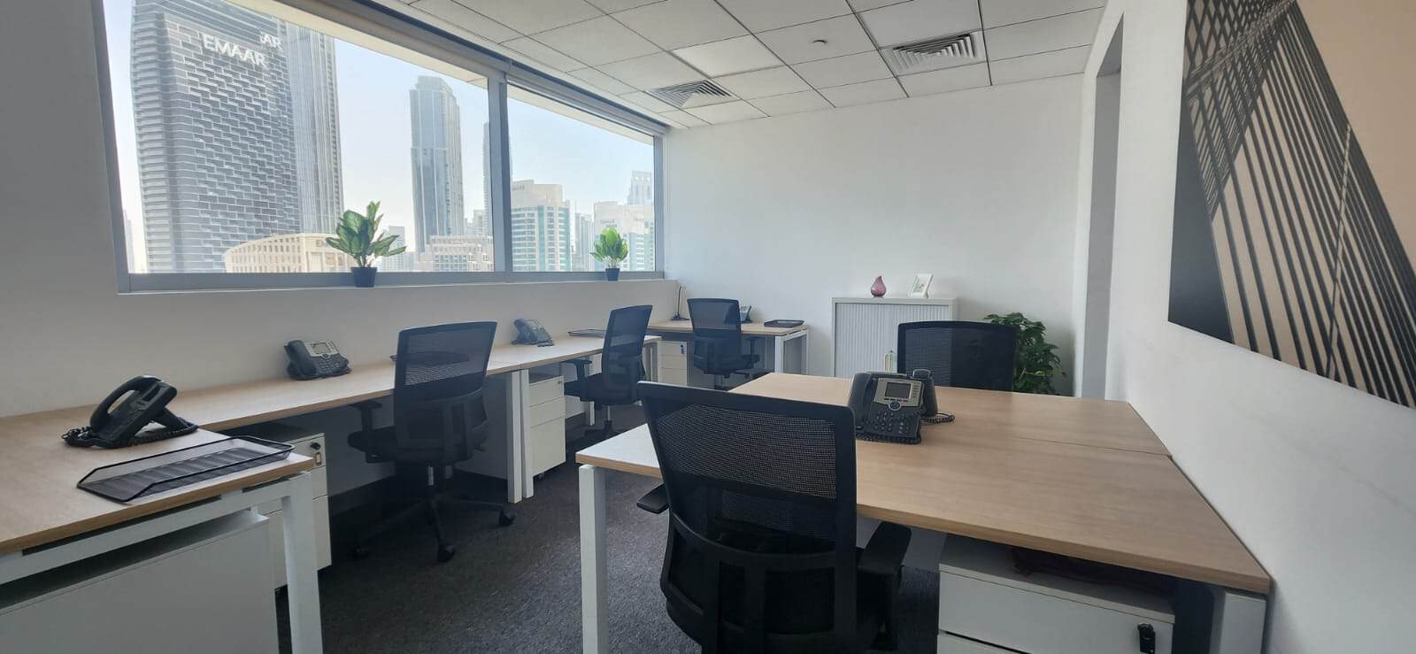 Bright office workspace with large windows overlooking Dubai’s skyscrapers and cityscape.