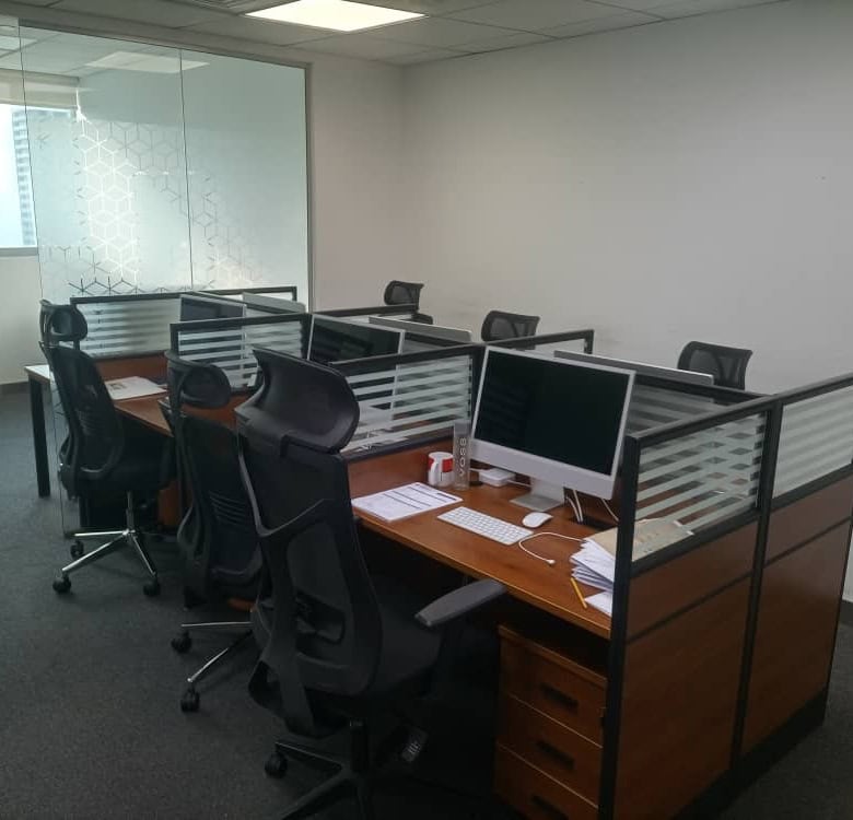 Office desks with computers and ergonomic chairs in a private workspace, ideal for remote working and startups in Dubai.