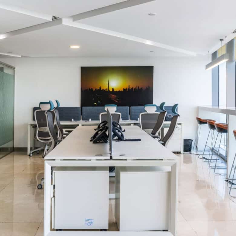 Bright, contemporary Dubai office with ergonomic chairs, meeting area, and skyline view for remote work.