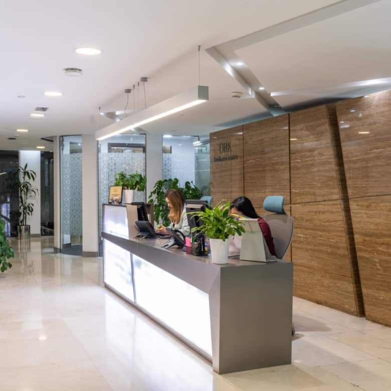 Modern reception desk with staff at work, lush green plants, welcoming office environment, business lounge in Dubai, coworking space UAE.