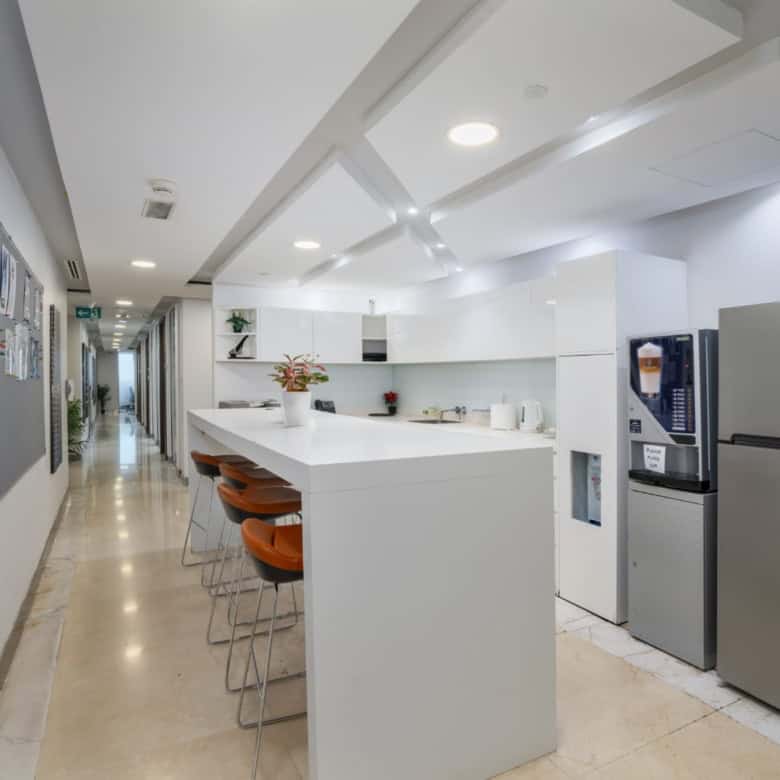 Bright, contemporary shared workspace kitchen with seating, appliances, and stylish decor in Dubai.