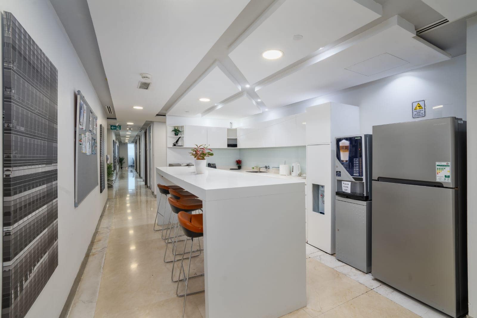 Bright, contemporary shared workspace kitchen with seating, appliances, and stylish decor in Dubai.