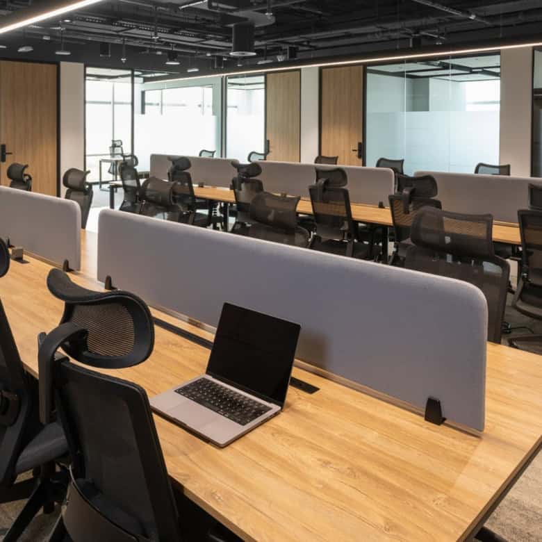 Bright, contemporary office with ergonomic chairs, work desks, partition screens, and a laptop. Perfect for startups and professionals in Dubai.