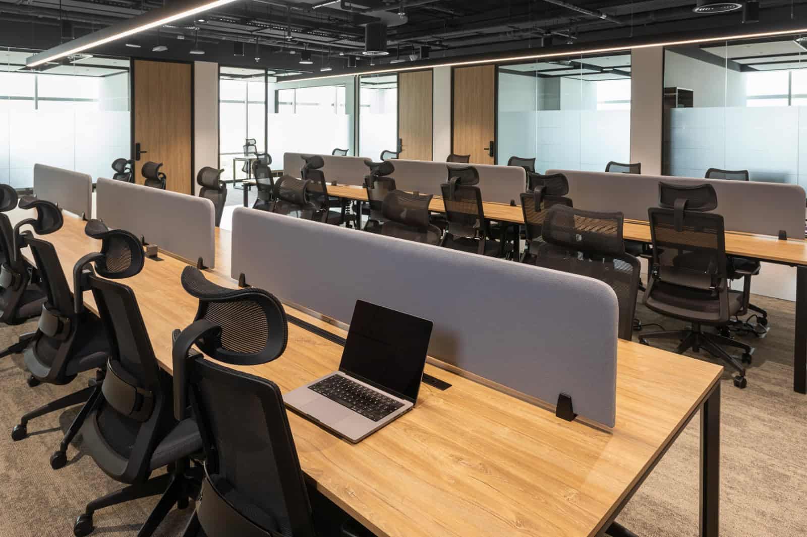 Bright, contemporary office with ergonomic chairs, work desks, partition screens, and a laptop. Perfect for startups and professionals in Dubai.