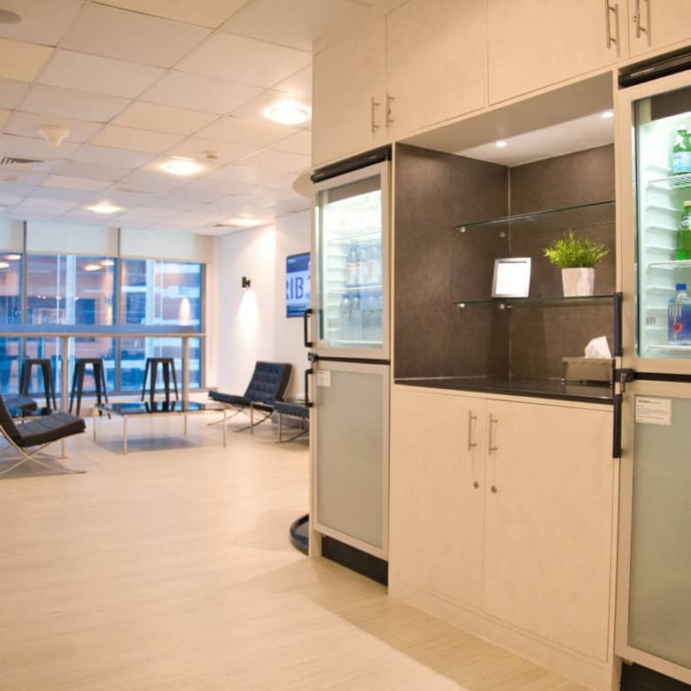 Bright office lounge with seating, large windows, and refreshment area in Dubai coworking space.