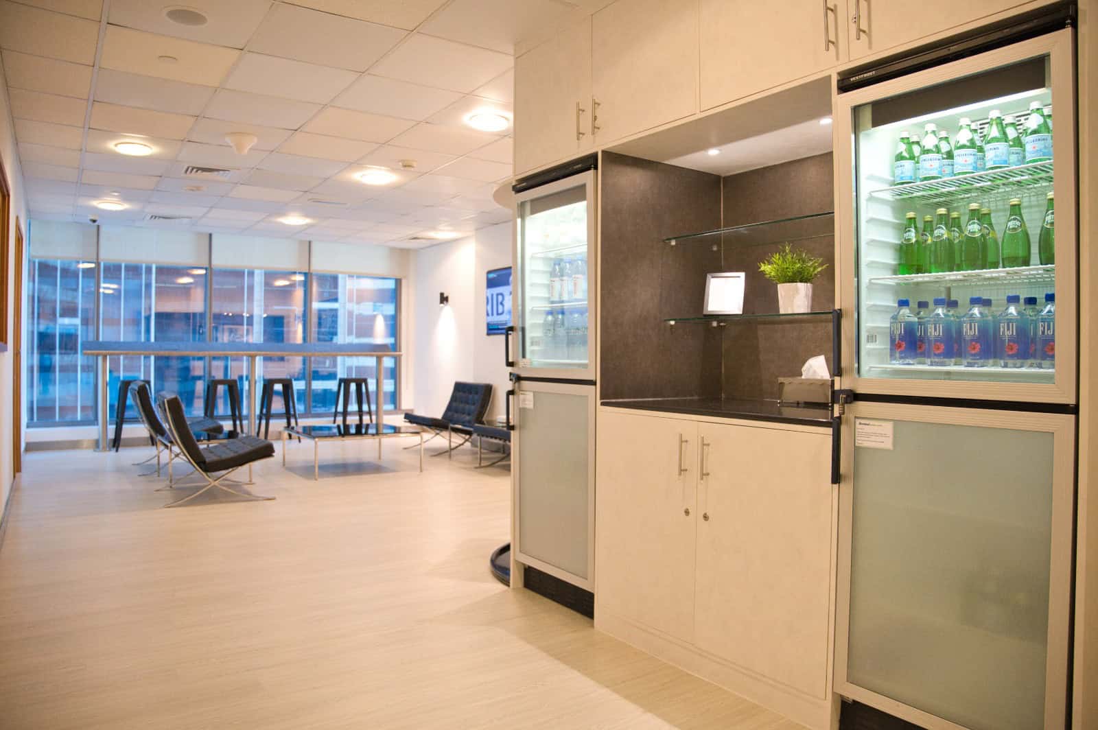 Bright office lounge with seating, large windows, and refreshment area in Dubai coworking space.