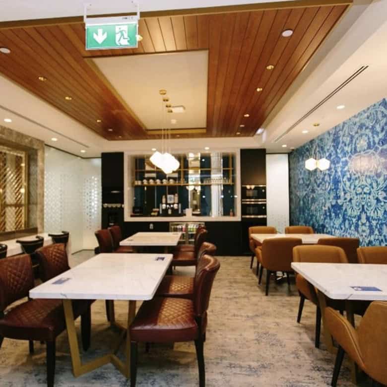 Spacious and stylish coworking restaurant in UAE with modern decor, lounge seating, and vibrant blue accent walls.