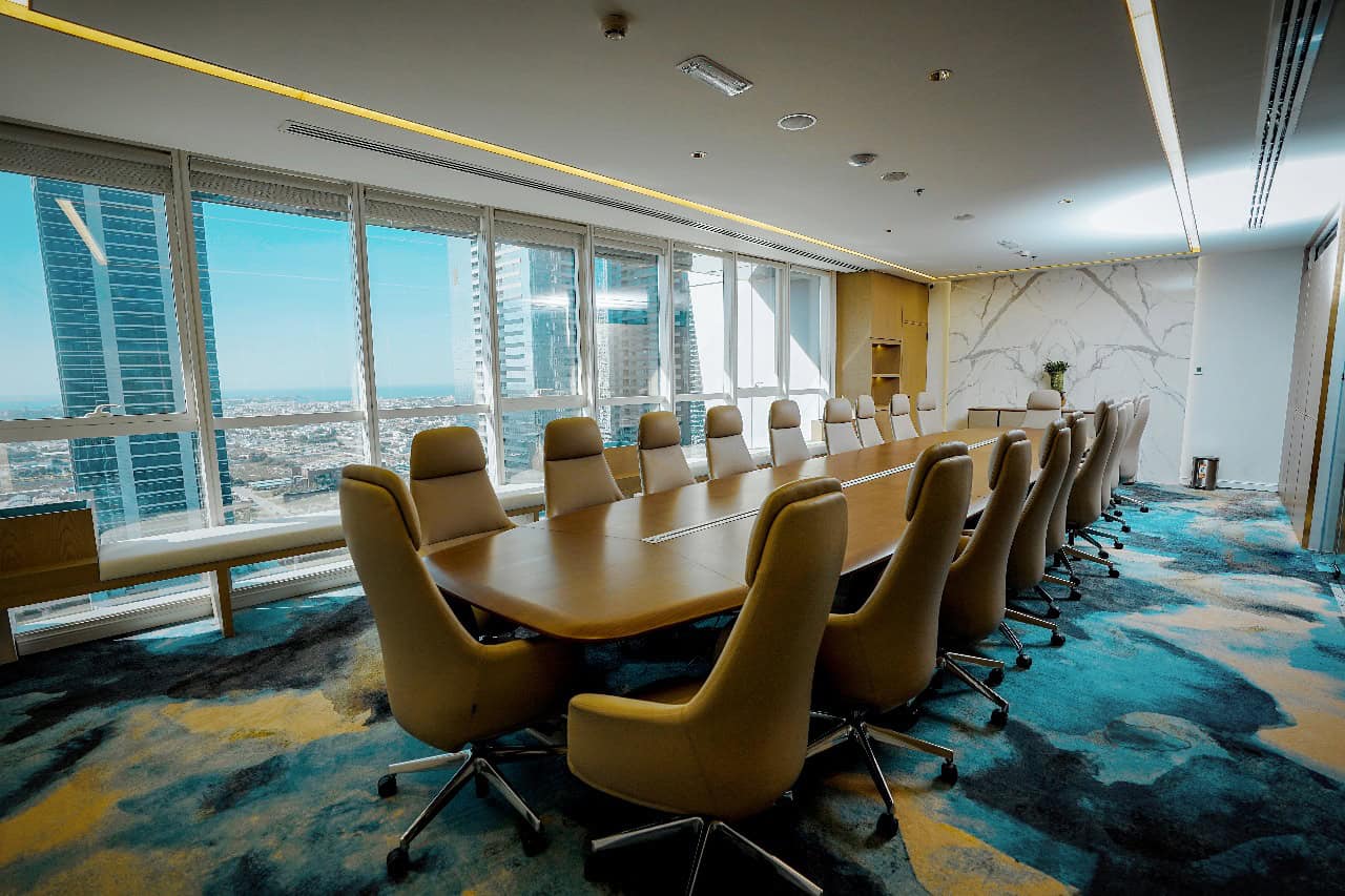 Spacious Dubai office with large windows, ergonomic chairs, and a high-tech conference table for professional gatherings.