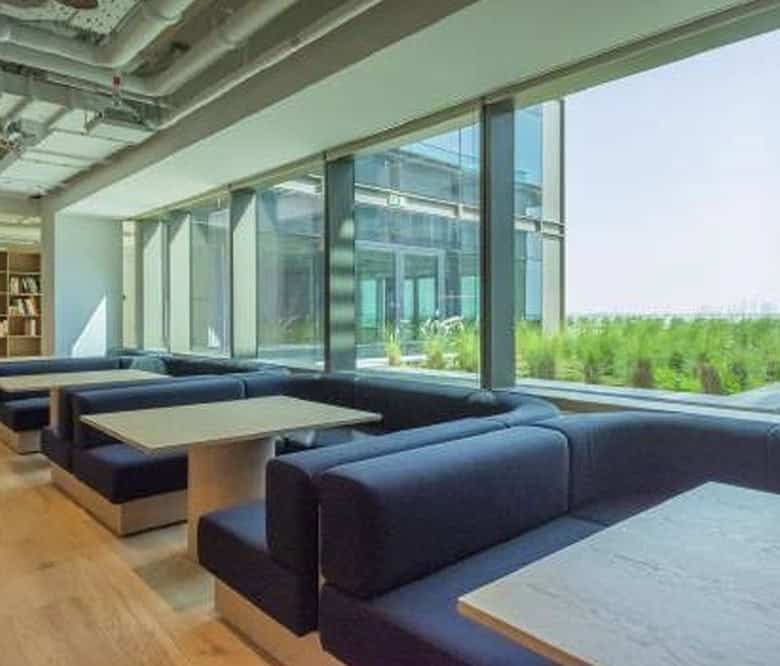 Spacious coworking lounge with large windows offering city skyline views at Nextspace UAE.
