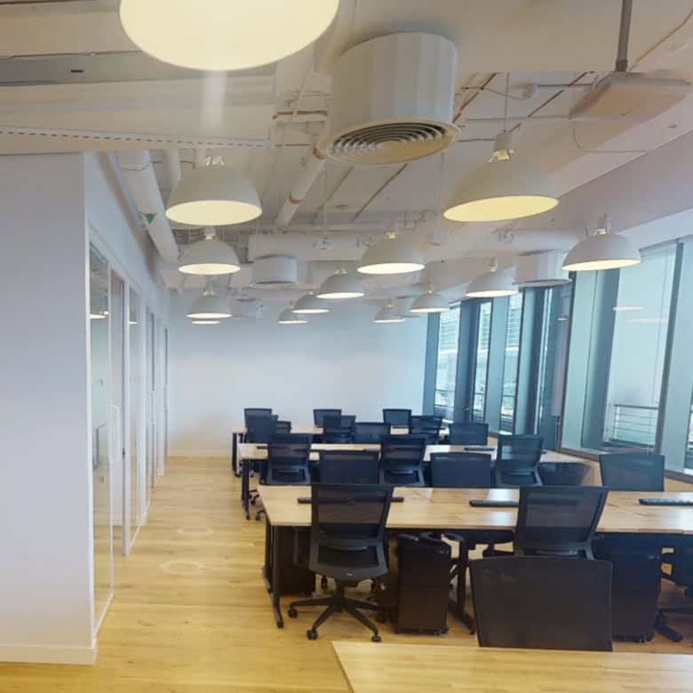 Bright coworking office space with panoramic city views, modern desks, and ergonomic chairs in Dubai.