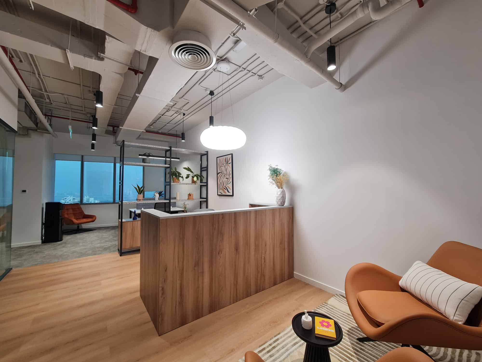 Furnished office lounge with stylish chairs, a reception area, and city view windows, ideal for productivity and networking.