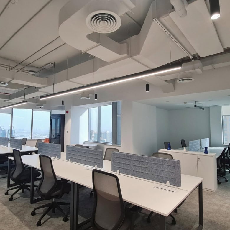 Modern coworking office in Dubai featuring open desks, ergonomic chairs, bright natural light, and modern interior design.