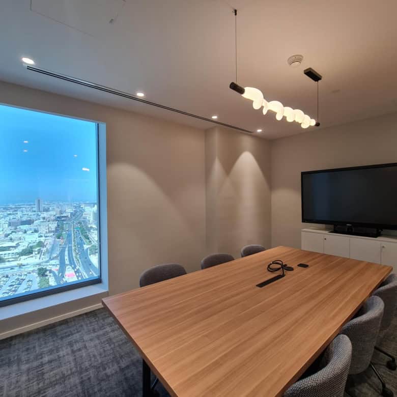High-quality image of a contemporary coworking office in Dubai with a city skyline view, meeting table, and modern decor for Nextspace UAE.