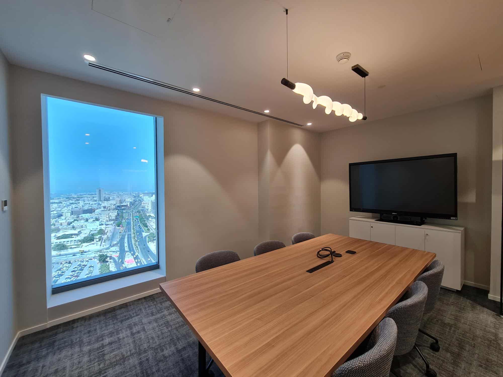 High-quality image of a contemporary coworking office in Dubai with a city skyline view, meeting table, and modern decor for Nextspace UAE.