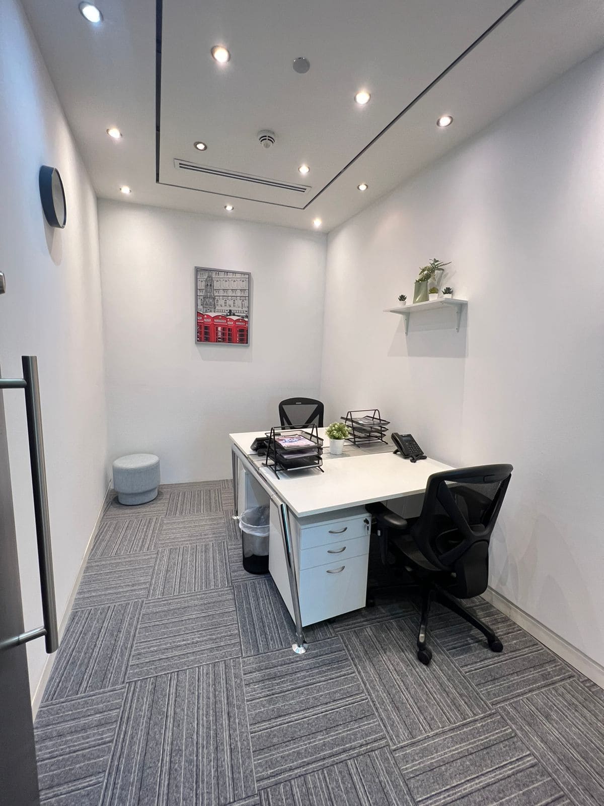 Cozy, minimalistic office interior with white walls, black chairs, and professional workspace setup.