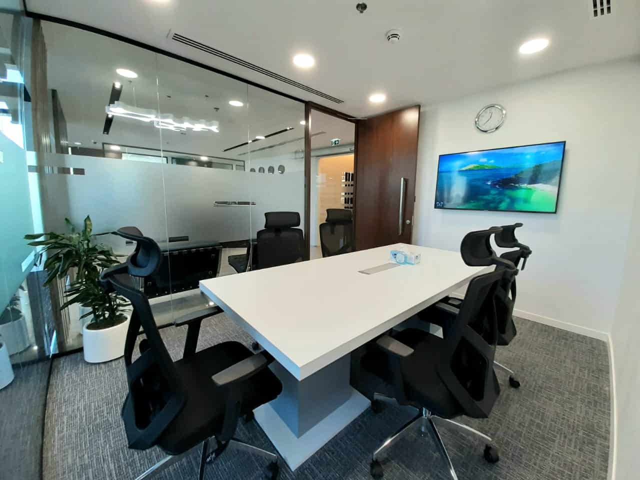 Bright, contemporary UAE coworking space with glass-enclosed meeting rooms, ergonomic chairs, and advanced tech amenities.