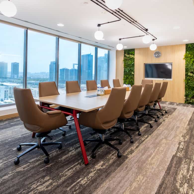 Spacious conference room in Nextspace UAE with comfortable chairs and a large TV screen.