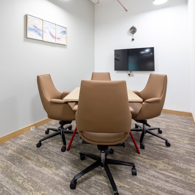 Comfortable beige office chairs, wall-mounted TV, minimalist decor, ideal for meetings and collaboration in Dubai.
