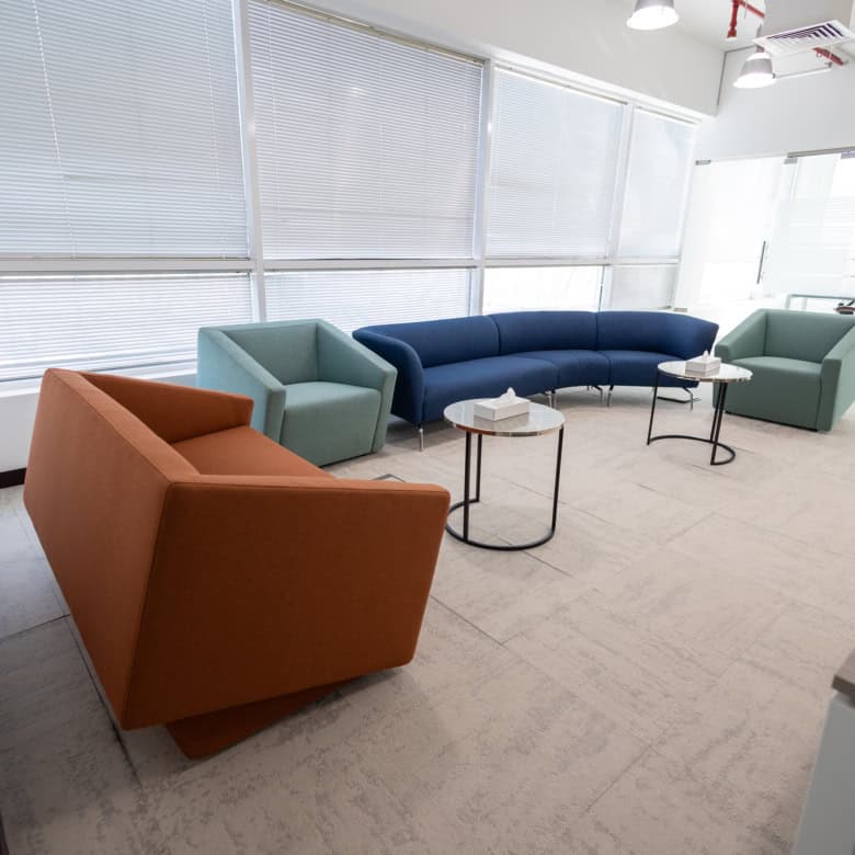 Vibrant coworking lounge with comfortable sofas, bright windows, and modern design, perfect for remote work or meetings.