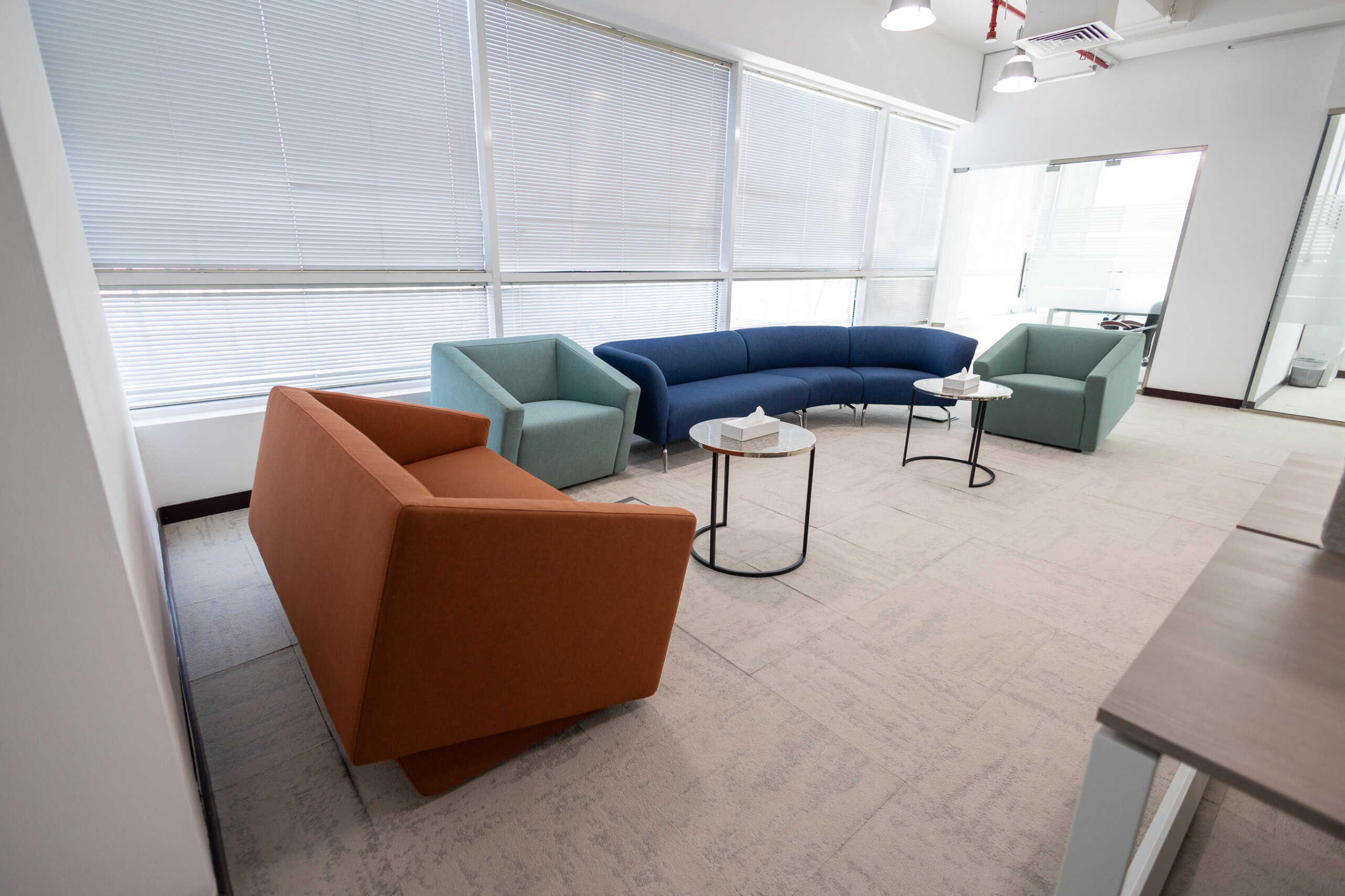 Vibrant coworking lounge with comfortable sofas, bright windows, and modern design, perfect for remote work or meetings.