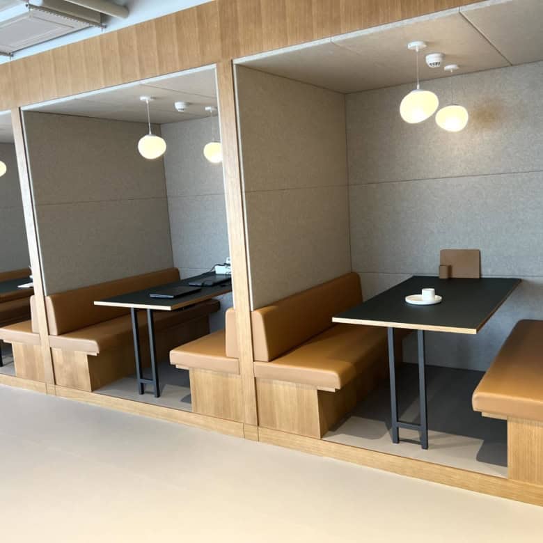 Cozy private booths in a contemporary coworking space with warm lighting and comfortable seating.