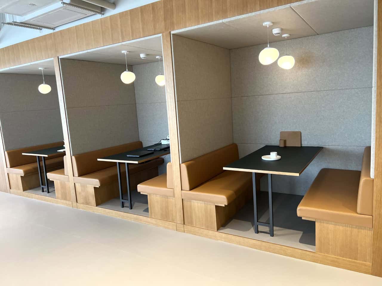 Cozy private booths in a contemporary coworking space with warm lighting and comfortable seating.