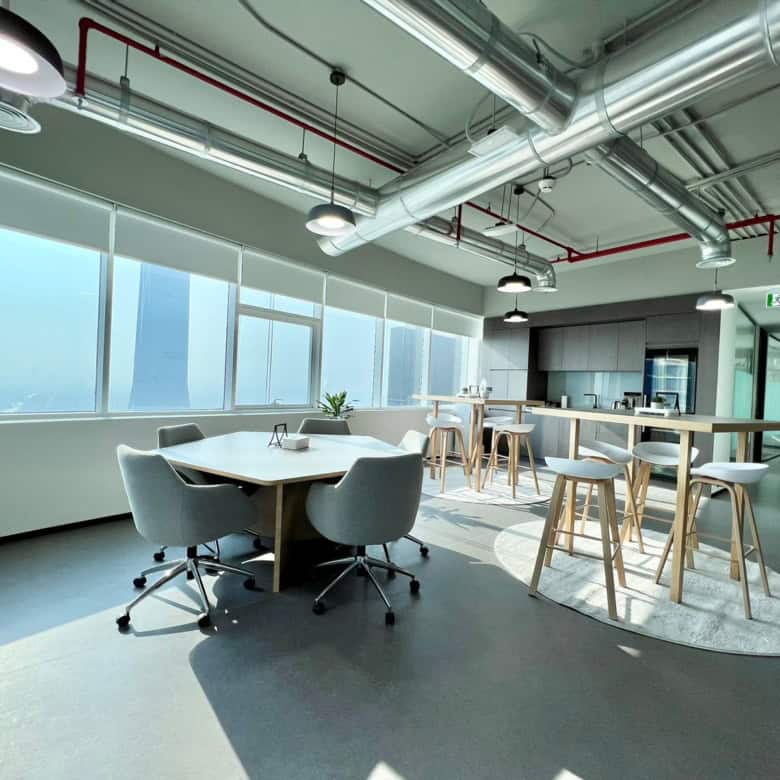 Bright coworking area with large windows, modern seating, and a high-rise city view at Nextspace UAE.