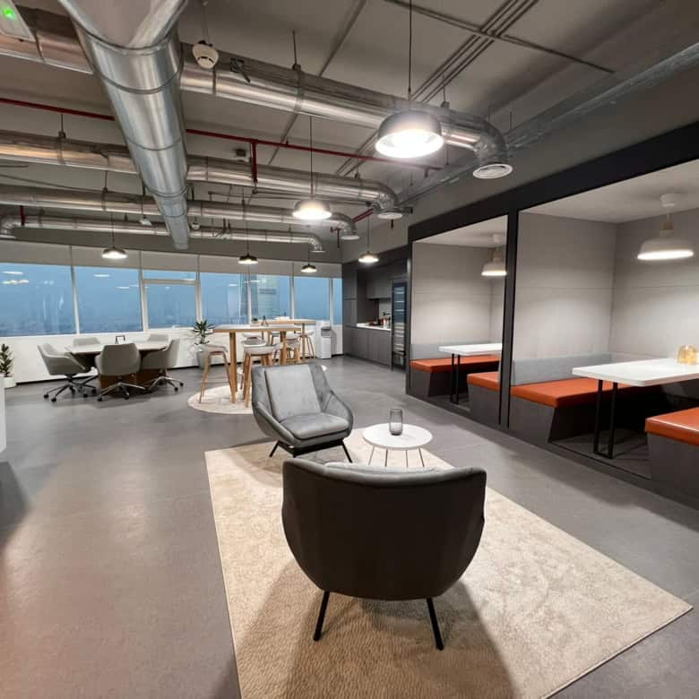 Contemporary office lounge with comfortable chairs, high ceilings, and large windows in Dubai.
