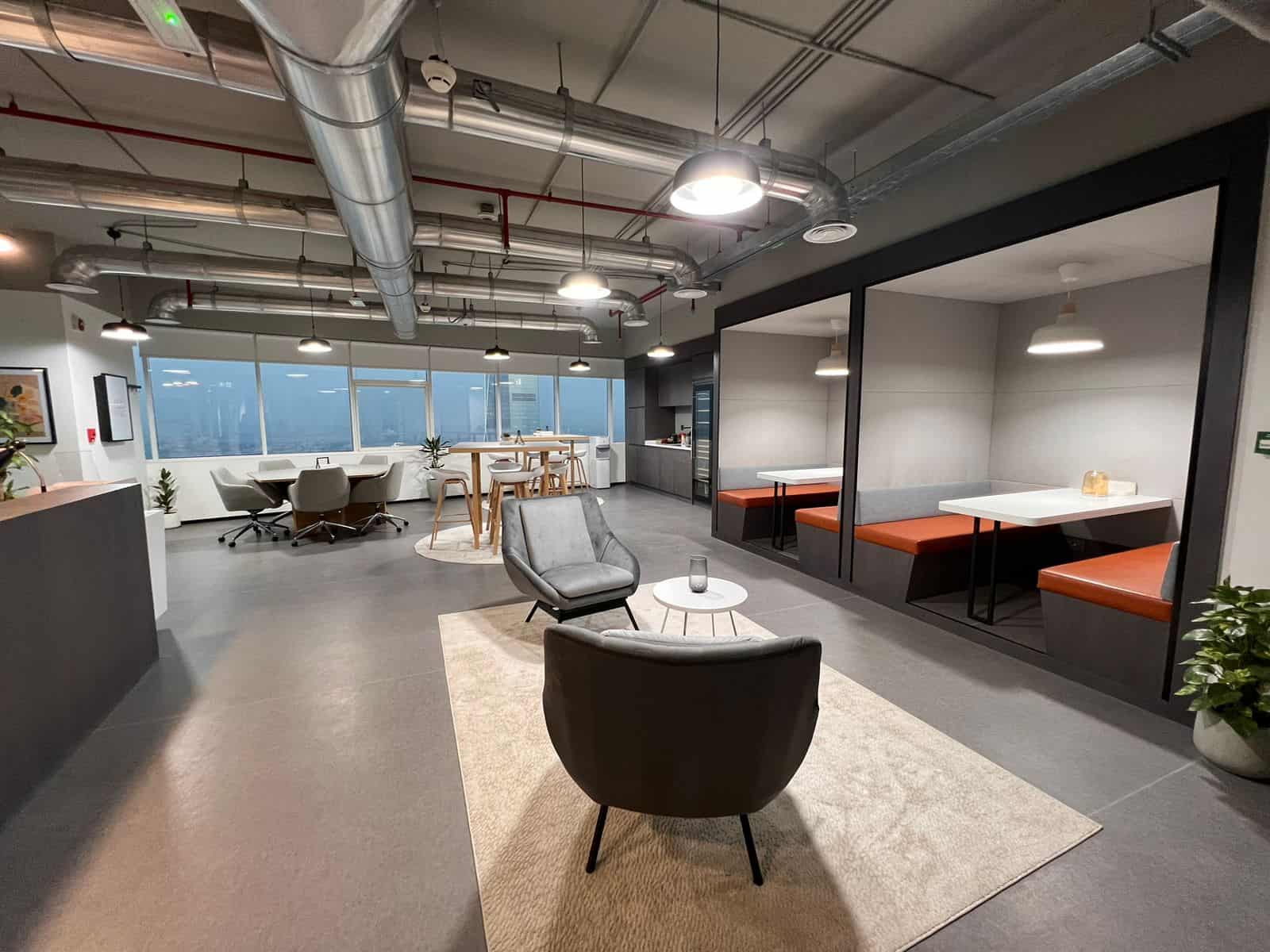 Contemporary office lounge with comfortable chairs, high ceilings, and large windows in Dubai.