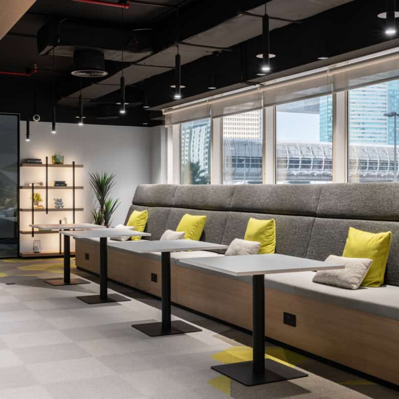 Bright coworking lounge with stylish seating, colorful cushions, and urban city views in Dubai.