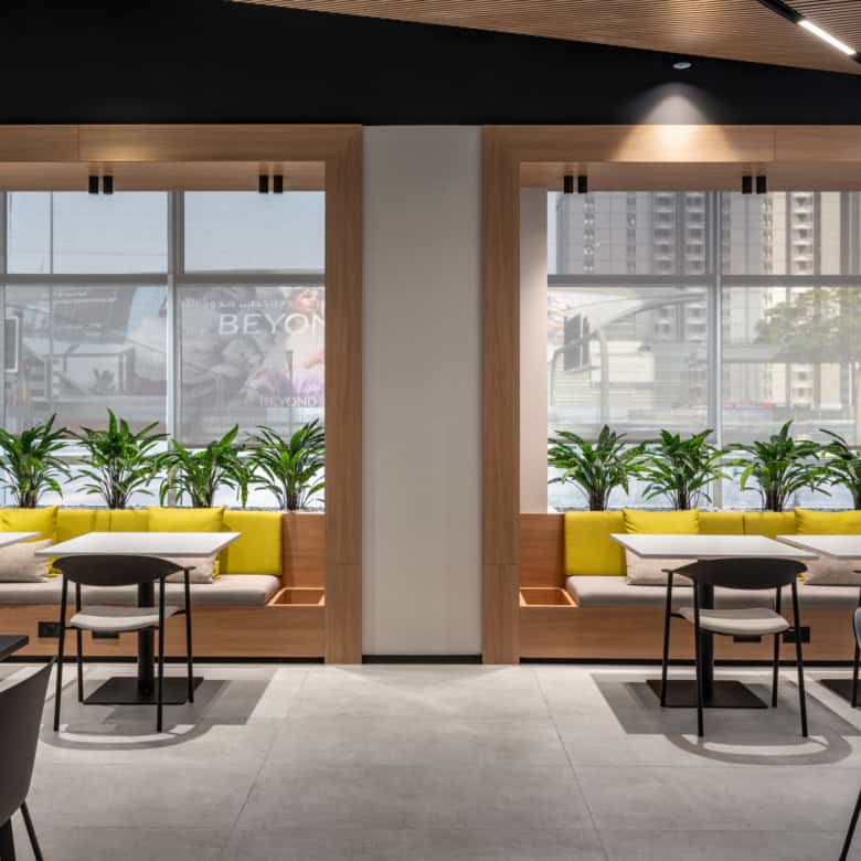 Bright coworking lounge featuring large windows, greenery, and contemporary decor at Nextspace UAE.