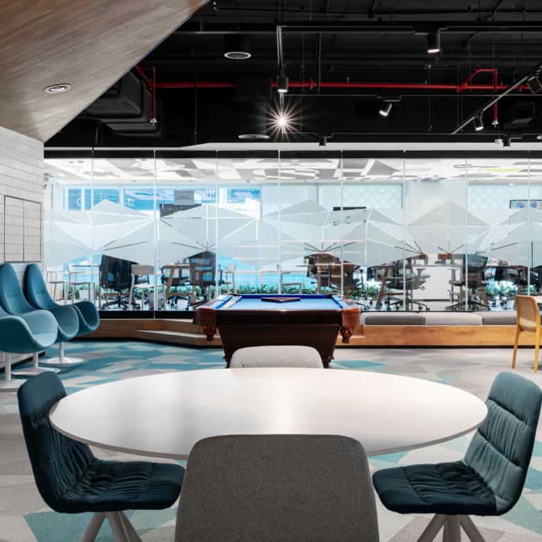 Bright coworking lounge with pool table, stylish seating, and glass walls, perfect for networking and relaxation.