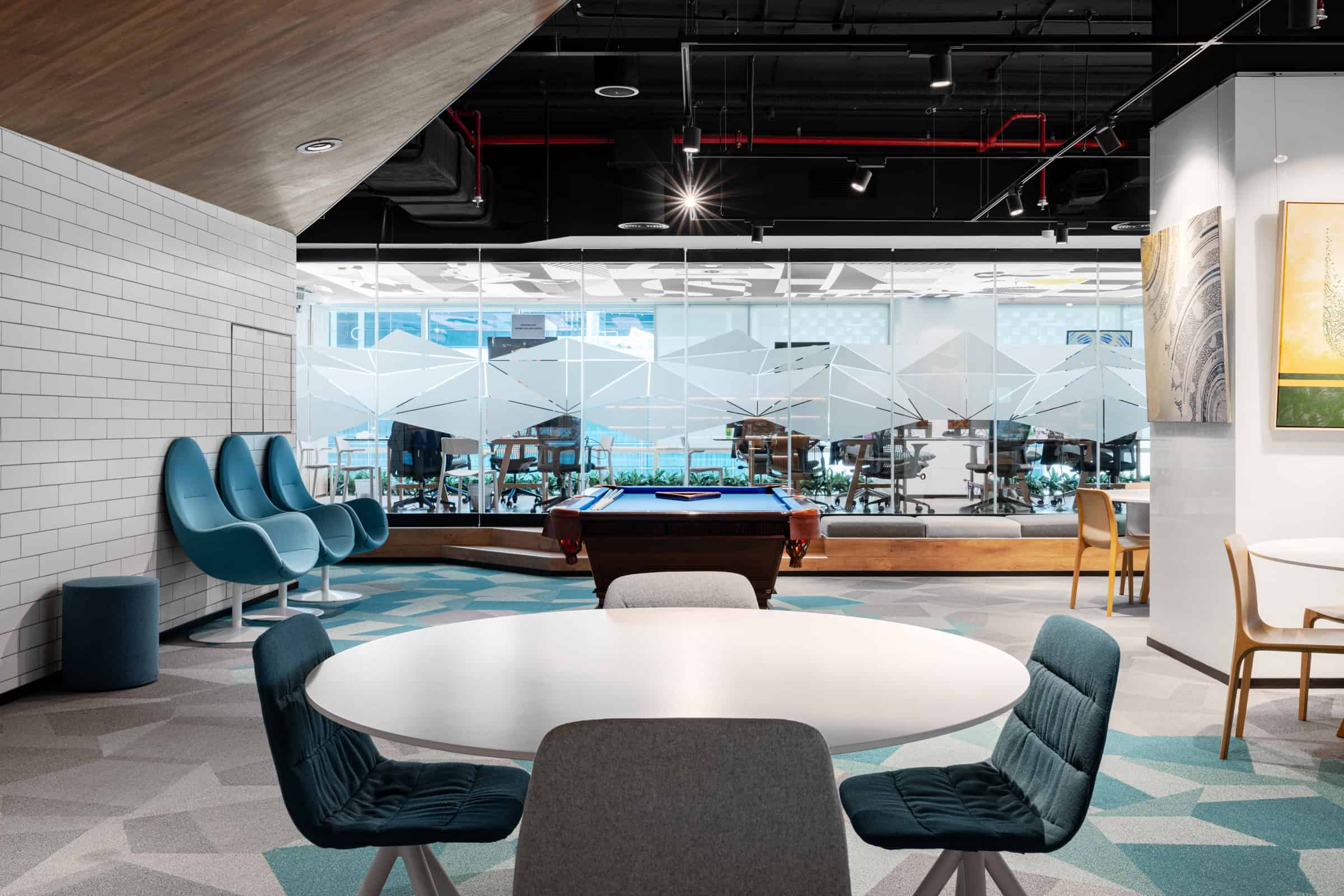 Modern coworking space in Dubai with bright lounge areas and a pool table, ideal for startups and freelancers. Bright coworking lounge with pool table, stylish seating, and glass walls, perfect for networking and relaxation.
