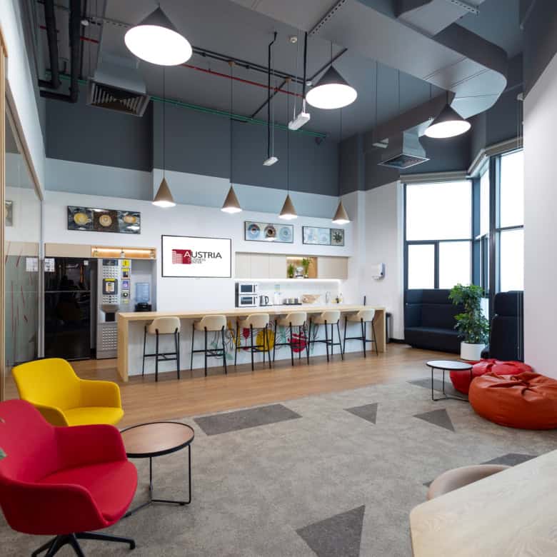 Bright, contemporary office lounge with colorful chairs, open plan design, and natural light.