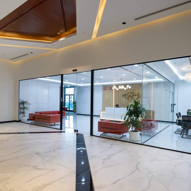 Elegant office interior with glass-walled conference rooms, contemporary furnishings, and ambient lighting.
