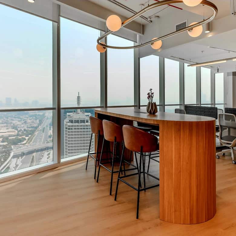Bright, stylish workspace with floor-to-ceiling windows, seating area, and scenic urban skyline views.