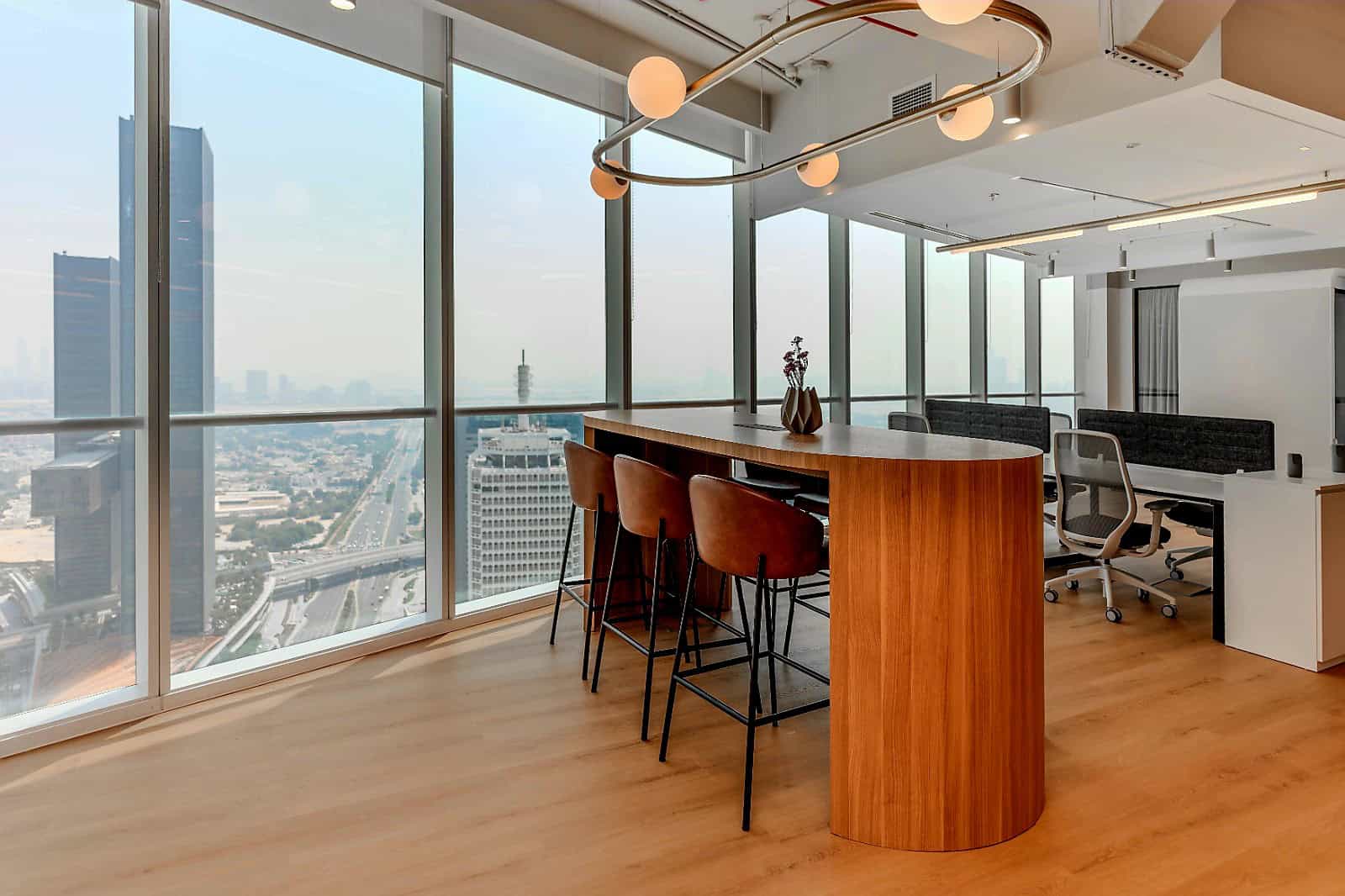 Bright, stylish workspace with floor-to-ceiling windows, seating area, and scenic urban skyline views.