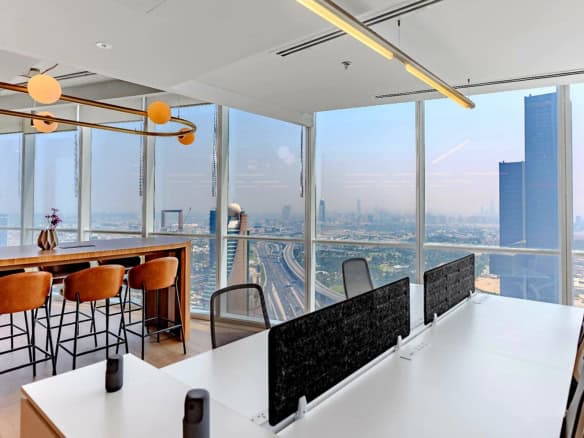 Modern office interior with large glass windows showcasing Dubai cityscape.