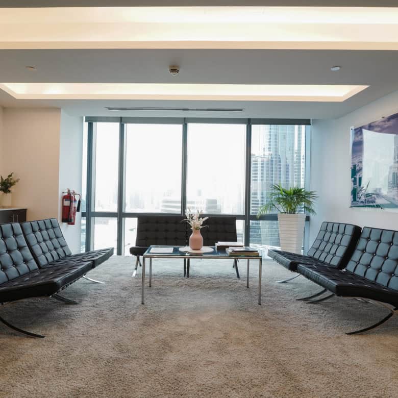 Luxurious office space with contemporary furniture, large windows, and panoramic city skyline in Dubai.
