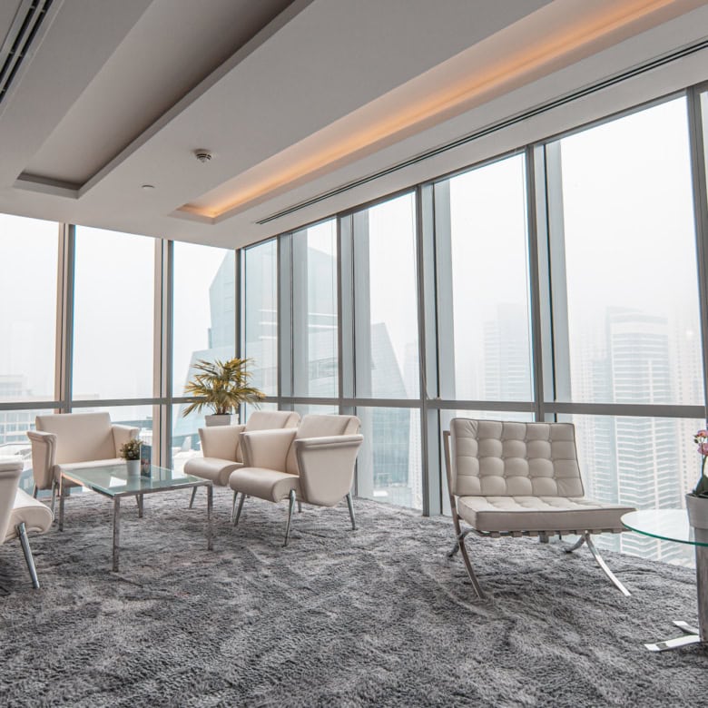 Bright coworking space with large windows, stylish seating, and urban skyline scenery in Dubai.
