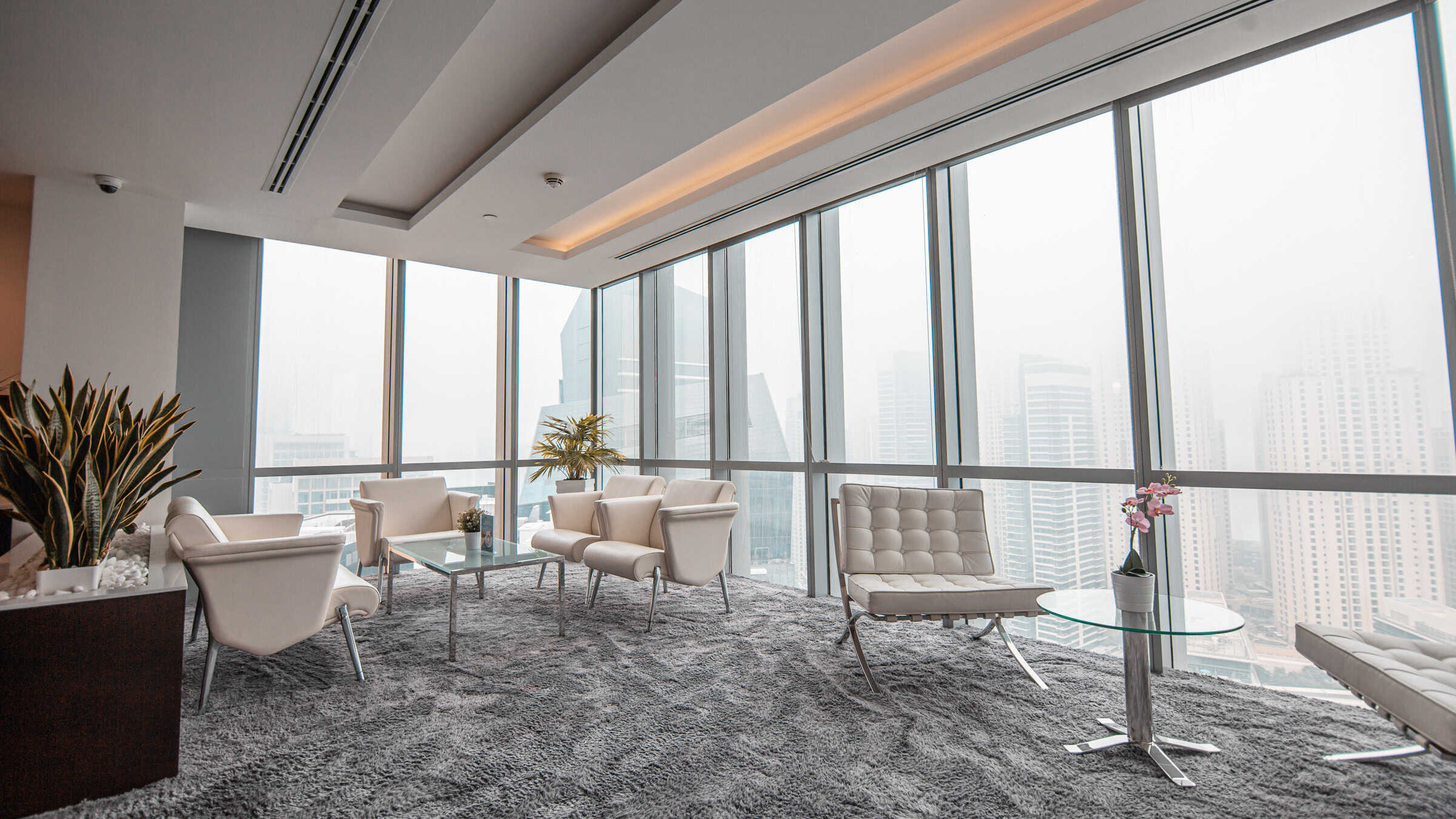 Bright coworking space with large windows, stylish seating, and urban skyline scenery in Dubai.