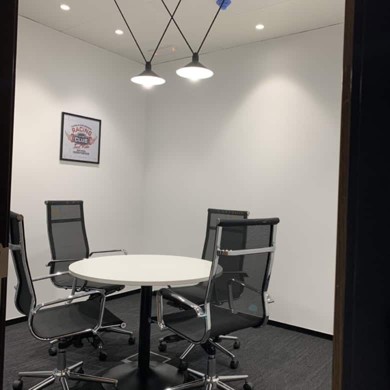 Bright office with round table and black mesh chairs for collaborative work.