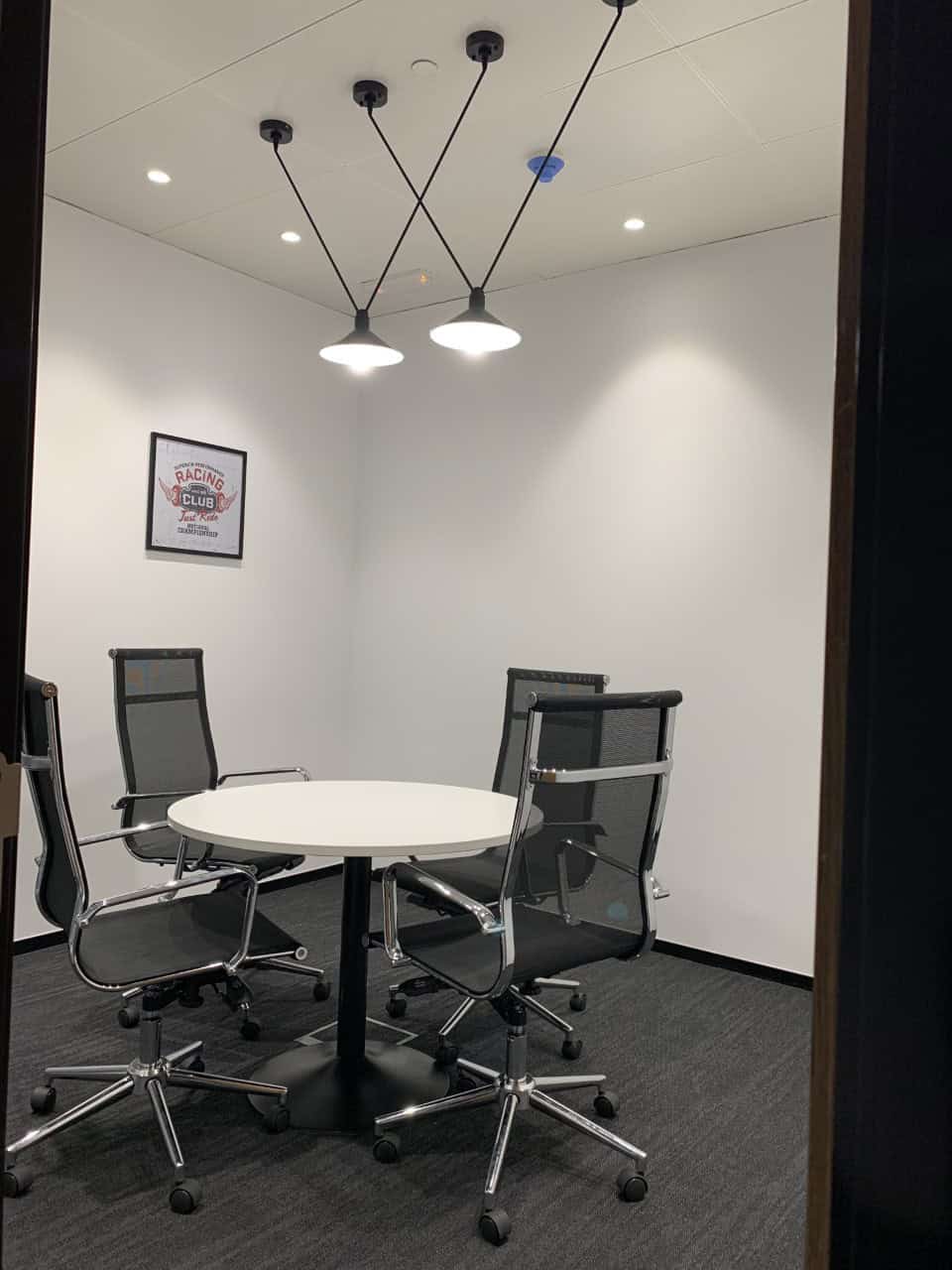 Bright office with round table and black mesh chairs for collaborative work.