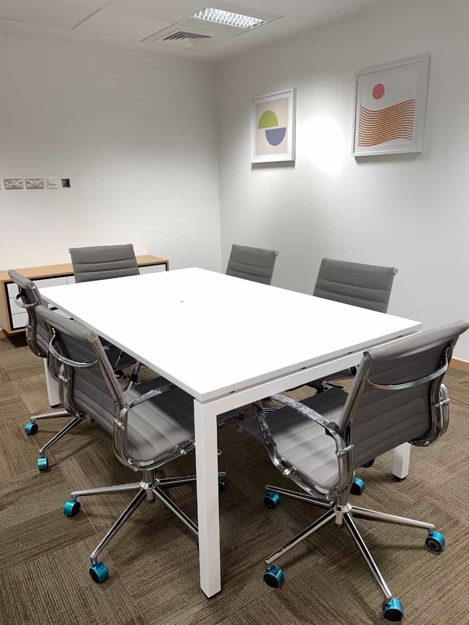 Contemporary meeting room with office chairs, artwork, and bright lighting at Nextspace UAE coworking space.