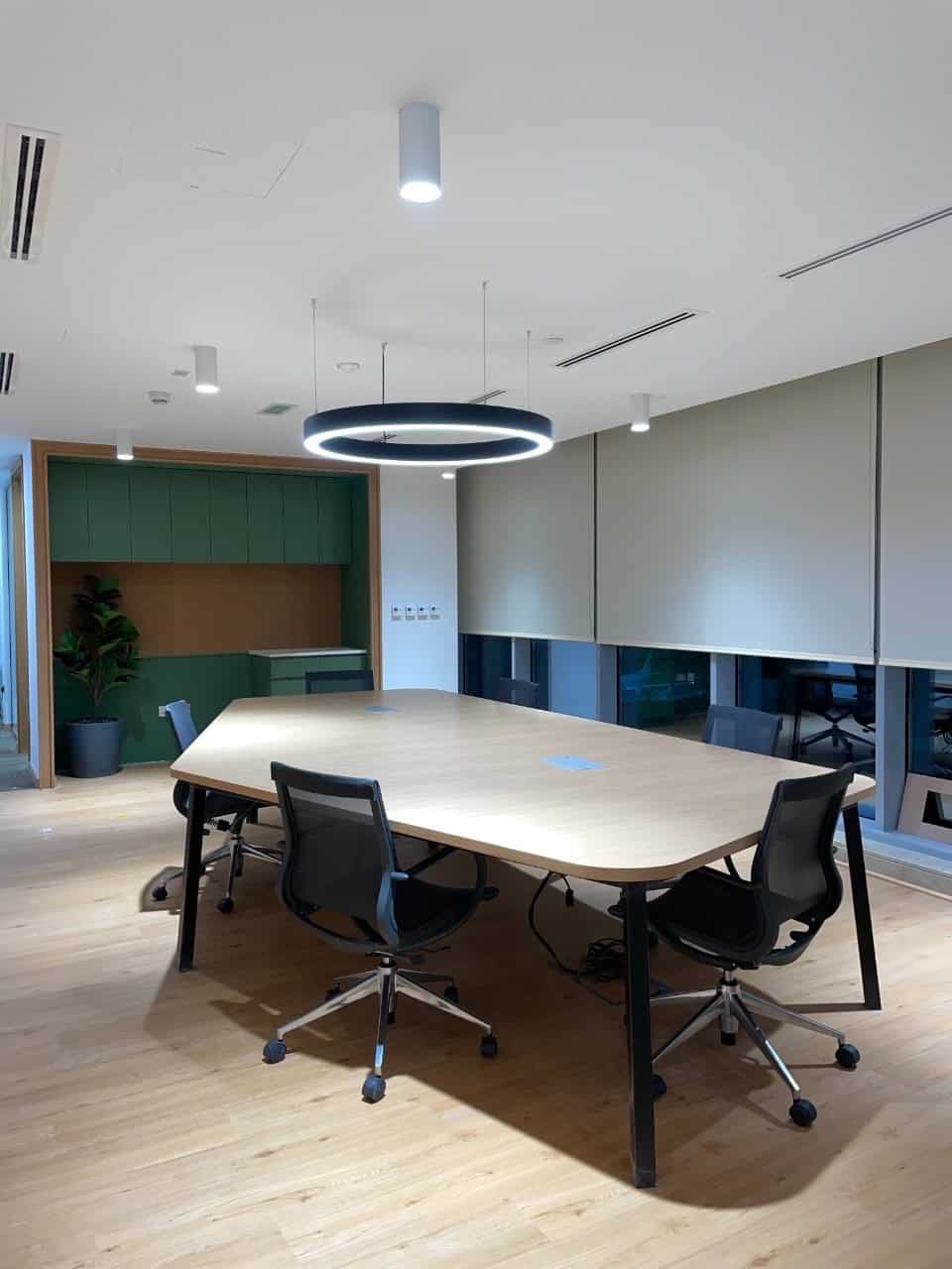 Bright, contemporary office meeting room featuring a large wooden table, black chairs, and sleek lighting for productivity.