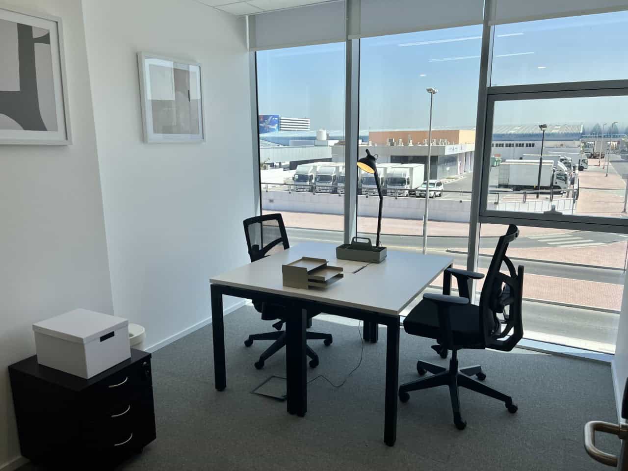 Office interior at Nextspace UAE with work desk, chairs, and natural sunlight.