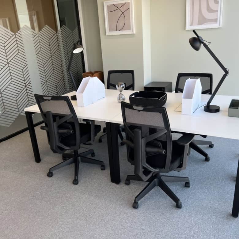 Clean, stylish office meeting room with ergonomic chairs, desks, and contemporary decor.