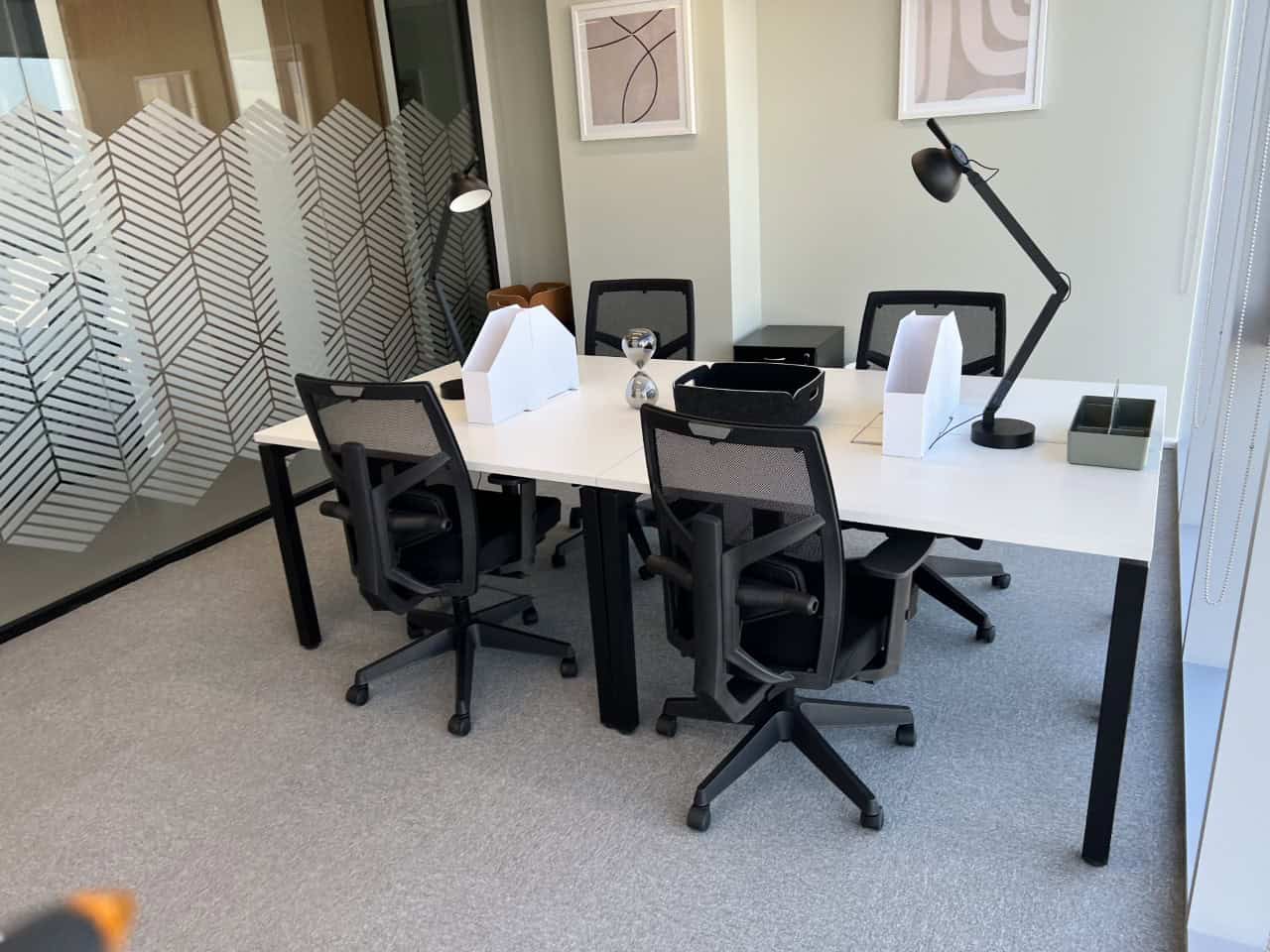 Clean, stylish office meeting room with ergonomic chairs, desks, and contemporary decor.